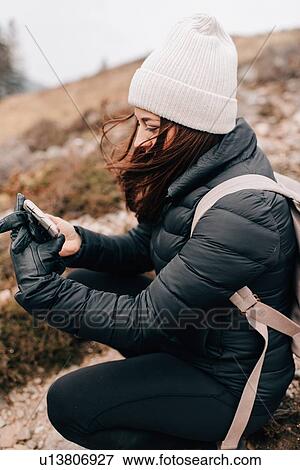 Stock Photo - Trekker kneeling to take selfie, Trossachs National Park, Canada. Fotosearch