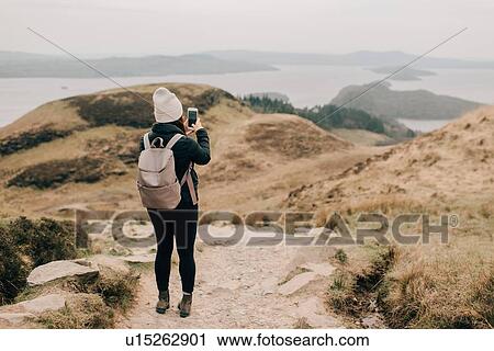 Stock Image - Trekker taking photo of Loch Lomond, Trossachs National Park, Canada. Fotosearch