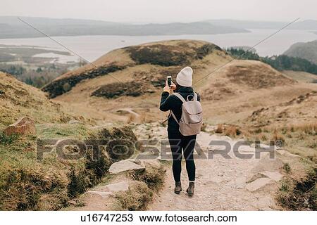 Stock Image - Trekker taking photo of Loch Lomond, Trossachs National Park, Canada. Fotosearch