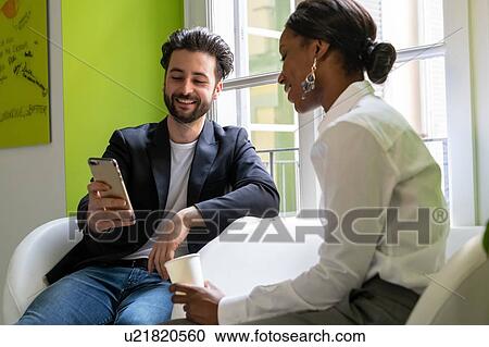 Two male and female business creatives looking at smartphone in office View Large Photo Image Stock Image - Two male and female business creatives looking at smartphone in office. Fotosearch