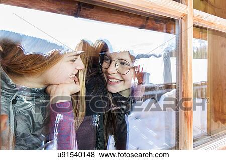 Stock Photo - Two teenage girl skiers chatting at cabin window, Tyrol, Styria, Austria. Fotosearch