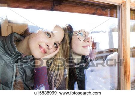 Stock Photo - Two teenage girl skiers looking out through cabin window, Tyrol, Styria, Austria. Fotosearch