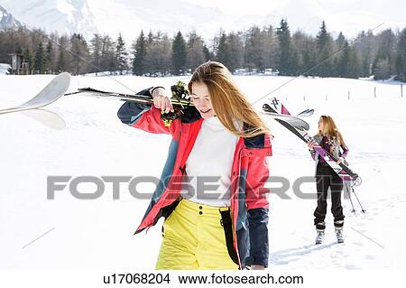 Picture - Two teenage girl skiers walking in snow covered landscape, Tyrol, Styria, Austria. Fotosearch