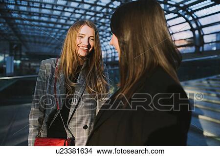 Picture - Two young women chatting on stairway in train station, Turin, Piemonte, Italy. Fotosearch