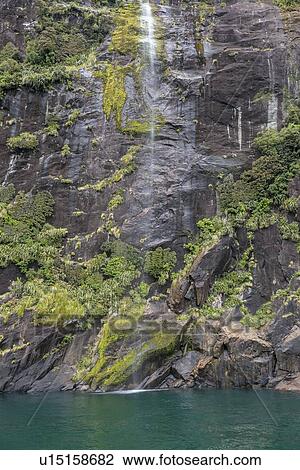 Stock Image - Waterfall in Milford Sound, New Zealand. Fotosearch