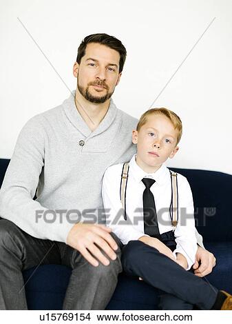Picture - Well-dressed father and son sitting on sofa. Fotosearch