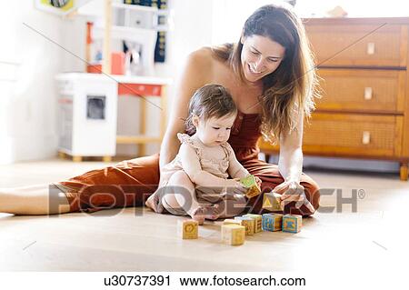 Woman and her baby daughter playing with toy blocks View Large Photo Image Stock Image - Woman and her baby daughter playing with toy blocks. Fotosearch