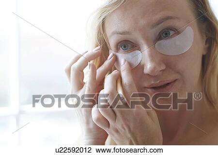Woman applying under-eye mask View Large Photo Image Stock Image - Woman applying under-eye mask. Fotosearch