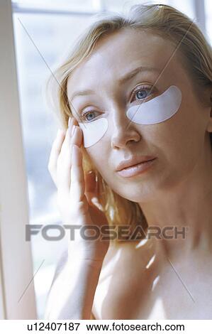 Stock Photo - Woman applying under-eye mask. Fotosearch