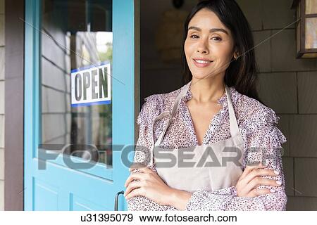 Stock Photo - Woman by door to shop with open sign. Fotosearch
