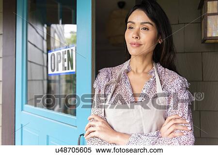 Stock Photography - Woman by door to shop with open sign. Fotosearch