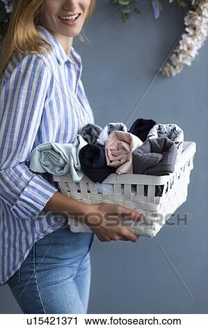 Stock Image - Woman carrying basket of fabrics. Fotosearch