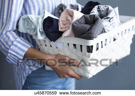 Stock Photo - Woman carrying basket of fabrics. Fotosearch