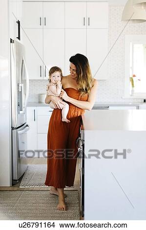 Woman carrying her baby daughter in kitchen View Large Photo Image Picture - Woman carrying her baby daughter in kitchen. Fotosearch