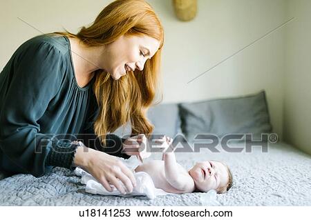 Woman changing her newborn son's nappy View Large Photo Image Stock Image - Woman changing her newborn son's nappy. Fotosearch