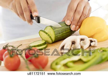 Stock Image - Woman chopping fresh cucumber.. Fotosearch