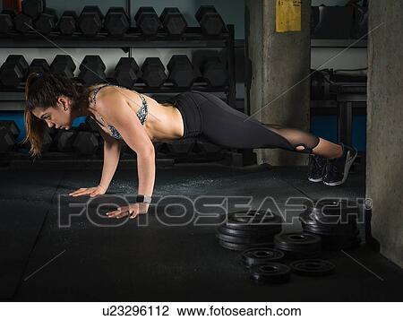 Stock Image - Woman doing plank in gym. Fotosearch