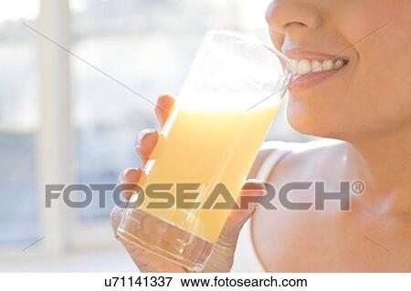 Stock Photo - Woman drinking fresh orange juice.. Fotosearch