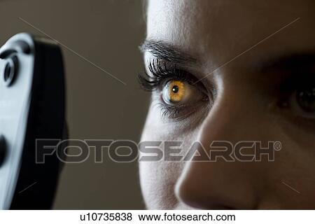 Stock Photo - Woman having eye test with light shining in iris.. Fotosearch