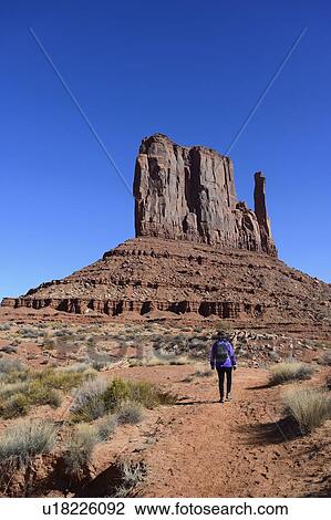 Stock Image - Woman hiking by butte in Monument Valley, Arizona, USA. Fotosearch