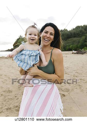 Woman holding baby daughter at beach View Large Photo Image Stock Image - Woman holding baby daughter at beach. Fotosearch