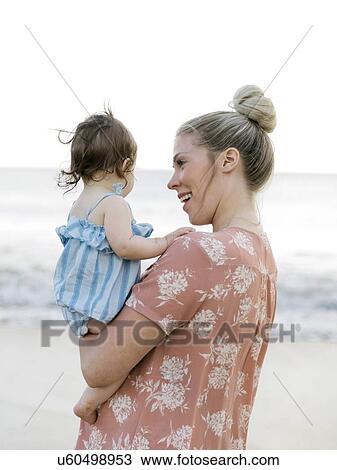Woman holding baby daughter on beach View Large Photo Image Stock Image - Woman holding baby daughter on beach. Fotosearch