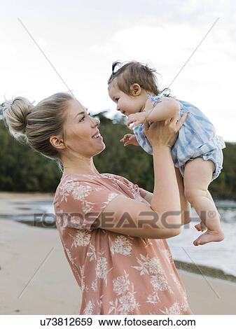 Woman holding baby daughter on beach View Large Photo Image Stock Photo - Woman holding baby daughter on beach. Fotosearch