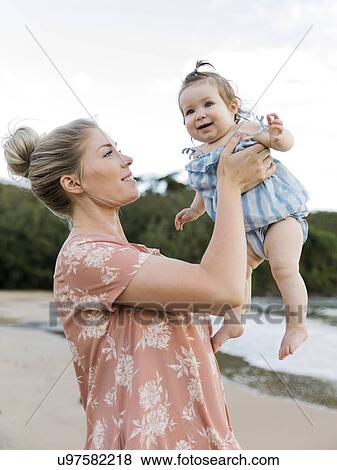 Stock Photo - Woman holding baby daughter on beach. Fotosearch