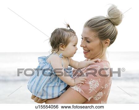Stock Photograph - Woman holding baby daughter on beach. Fotosearch