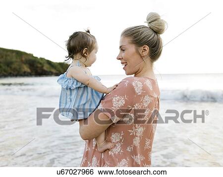 Woman holding baby daughter on beach View Large Photo Image Stock Photograph - Woman holding baby daughter on beach. Fotosearch