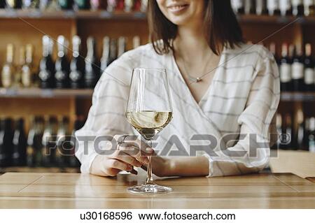 Stock Photograph - Woman holding glass of white wine. Fotosearch