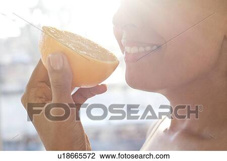 Stock Image - Woman holding half an orange.. Fotosearch