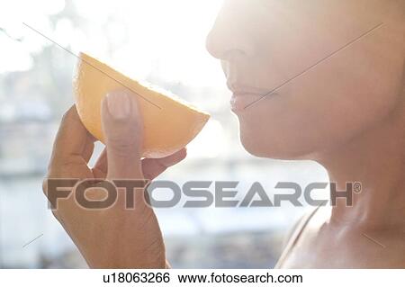 Stock Photograph - Woman holding half an orange.. Fotosearch