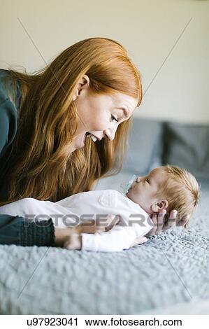 Stock Image - Woman holding her newborn son on bed. Fotosearch