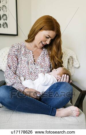 Woman holding her newborn son on armchair View Large Photo Image Stock Photograph - Woman holding her newborn son on armchair. Fotosearch