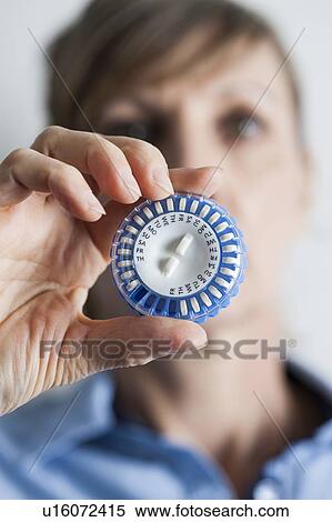 Stock Photography - Woman holding hormone replacement therapy (HRT) pills. HRT pills are synthetic hormones used to treat menopausal women. They counteract the hormone deficiency that occurs at menopause.. Fotosearch