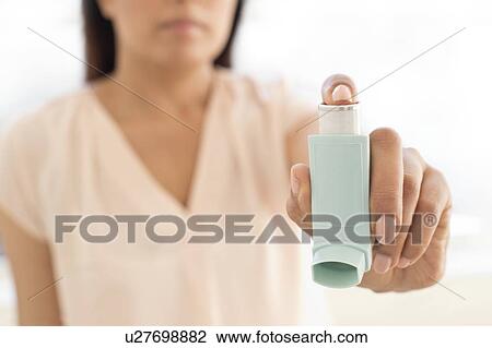 Stock Image - Woman holding inhaler.. Fotosearch
