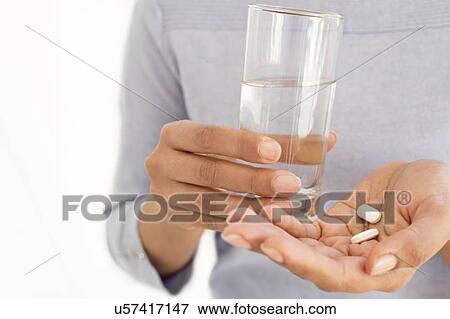 Woman holding painkiller tablets and glass of water. View Large Photo Image Stock Photo - Woman holding painkiller tablets and glass of water.. Fotosearch