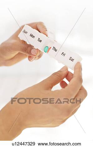 Stock Photo - Woman holding pill organiser.. Fotosearch