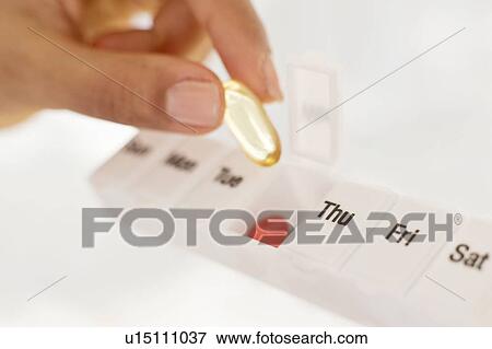Stock Photo - Woman holding pill organiser.. Fotosearch