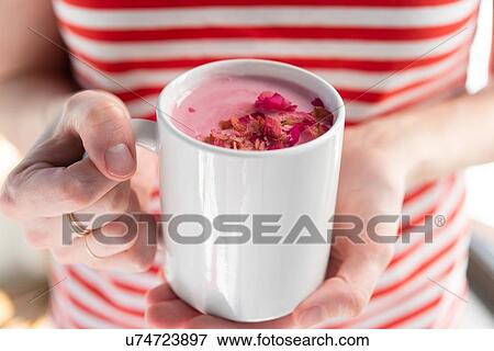 Stock Photo - Woman holding pink drink topped with petals. Fotosearch