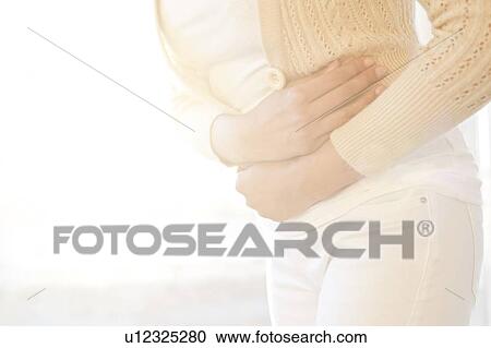 Stock Image - Woman holding stomach in pain.. Fotosearch
