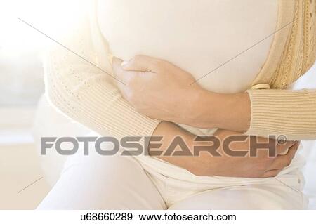 Stock Photo - Woman holding stomach in pain.. Fotosearch