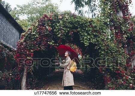 Woman holding umbrella by vine covered arch View Large Photo Image Stock Photograph - Woman holding umbrella by vine covered arch. Fotosearch