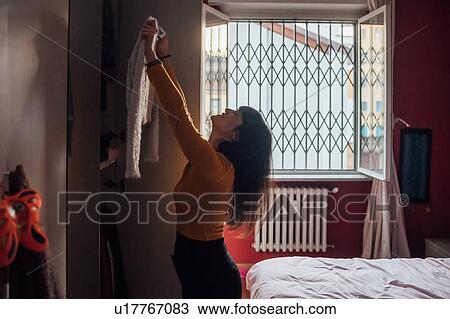 Woman holding up new top in bedroom View Large Photo Image Stock Image - Woman holding up new top in bedroom. Fotosearch