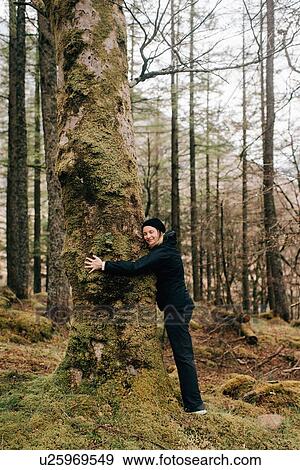Stock Photo - Woman hugging tree, Trossachs National Park, Canada. Fotosearch