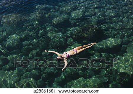 Stock Image - Woman in bikini swimming in sea. Fotosearch