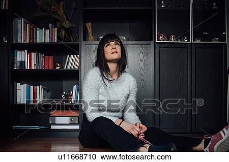 Stock Image - Woman in deep thought on floor. Fotosearch