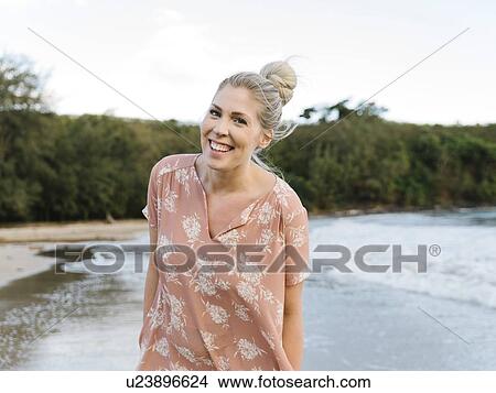 Picture - Woman in floral pattern dress at beach. Fotosearch
