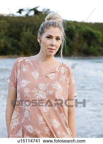 Stock Image - Woman in floral pattern dress at beach. Fotosearch